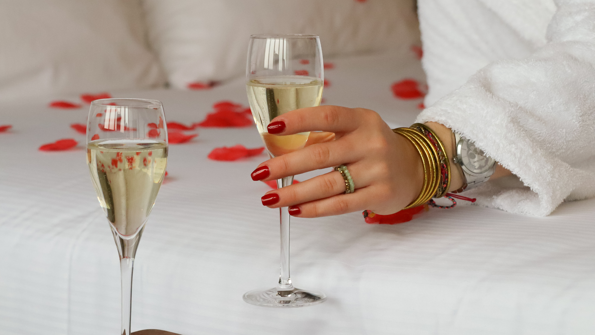 Main tenant une coupe de champagne sur lit.