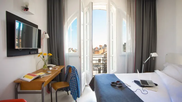 Chambre d'hôtel lumineuse avec vue sur la ville.