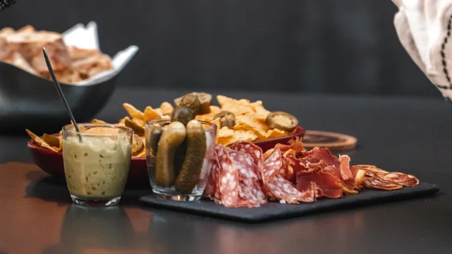 Assortiment charcuterie, cornichons, chips, sauce sur table.